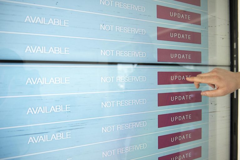 A hand interacts with a digital touchscreen interface showing availability and update options.