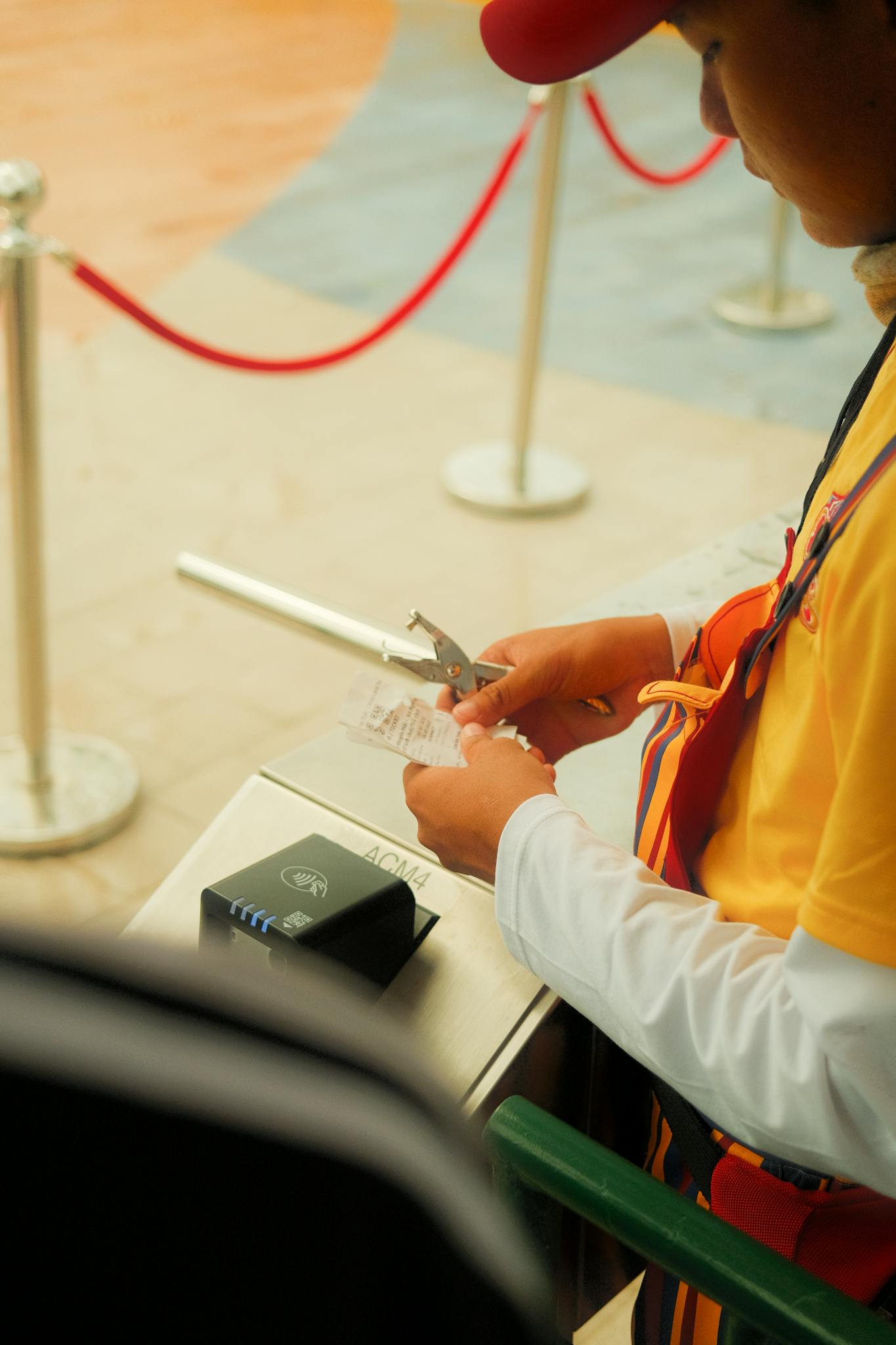 A worker in uniform processes tickets at an event gate, ensuring visitor entry.