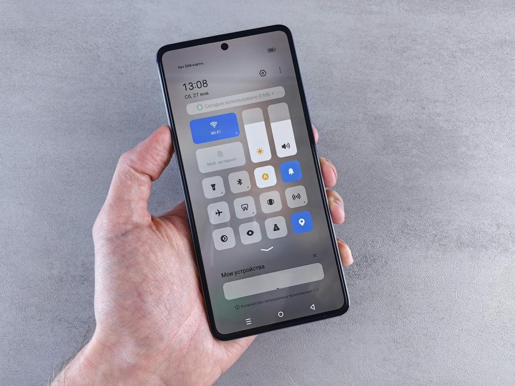Close-up of a hand holding a smartphone with settings panel visible, focus on screen.
