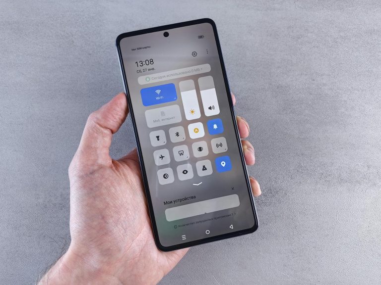Close-up of a hand holding a smartphone with settings panel visible, focus on screen.