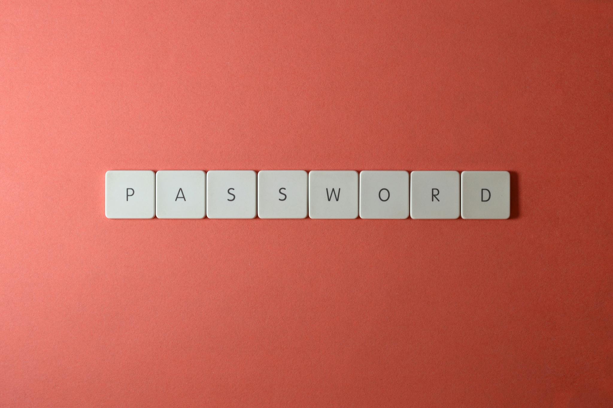 Focus on password security with white keyboard tiles spelling 'PASSWORD' on a coral background.